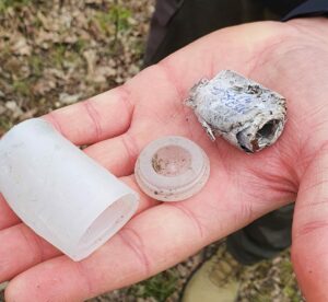 Hand mit Papier und Waldboden. Geocaching fund
