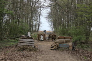 Waldweg mit Bäumen Europaletten als Wegsperre und 2 Personen