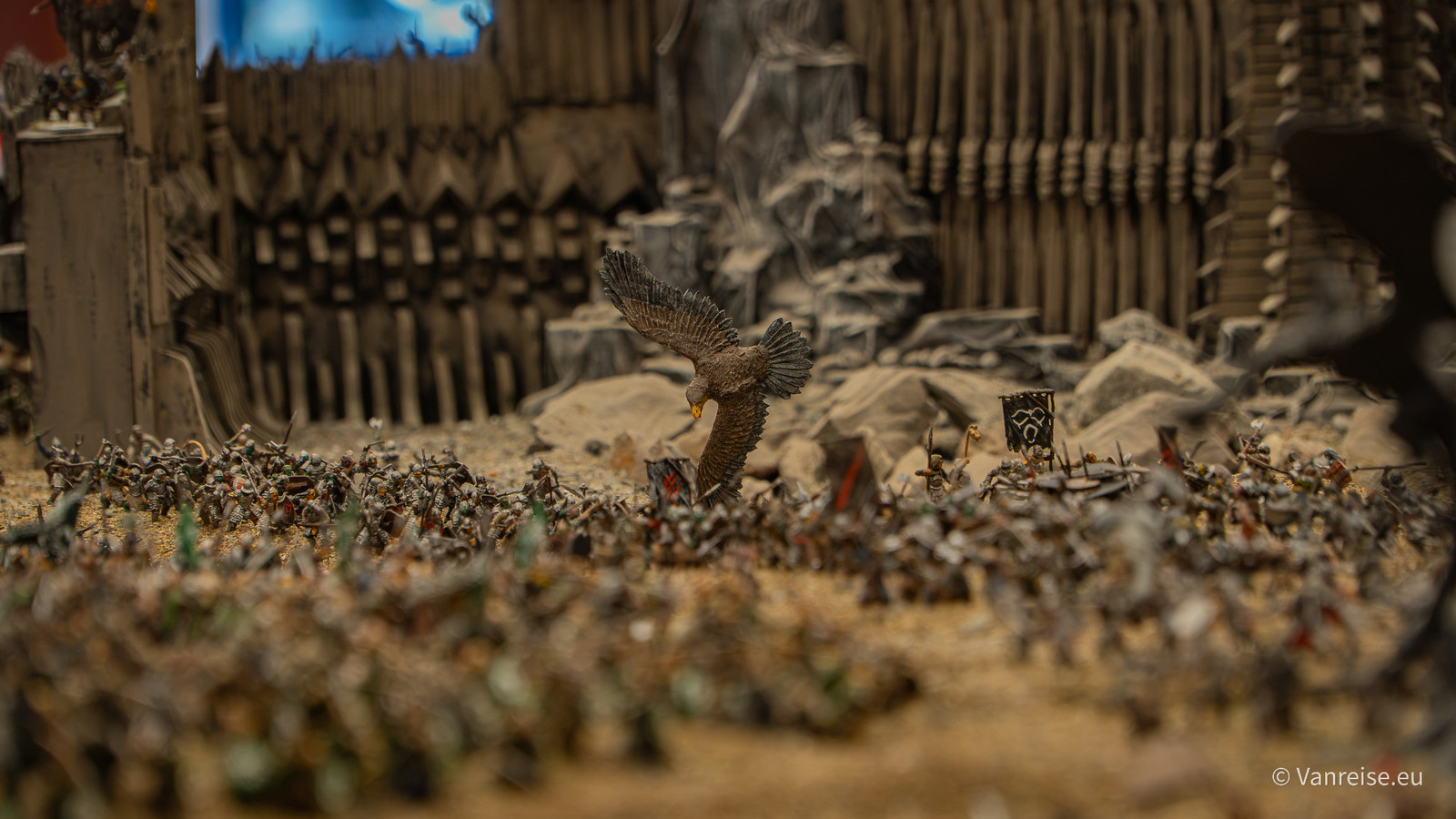 Fantasy-Diorama mit vielen Miniaturfiguren, einer Adlerfigur und hohen Festungsmauern im Hintergrund.