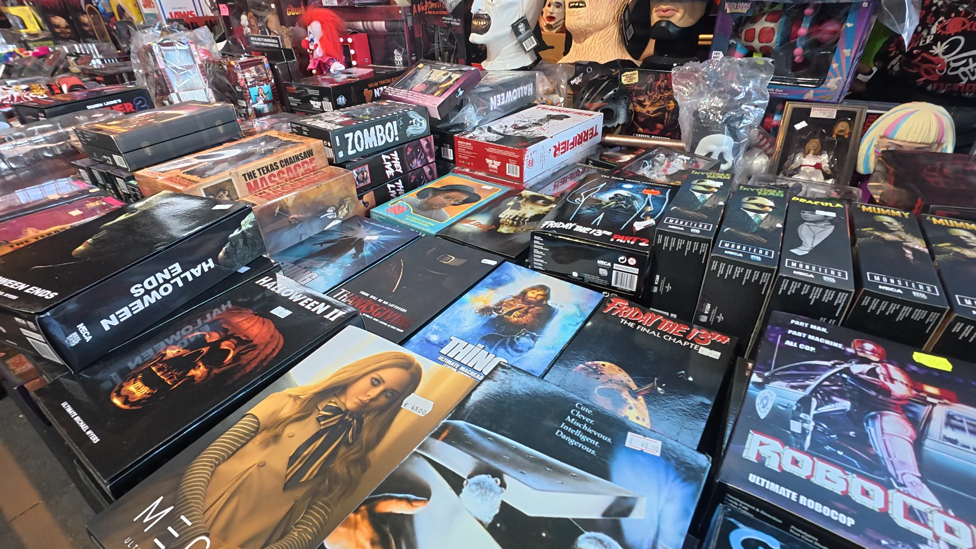 Händlertisch mit verpackten Horrorfilmfiguren und weiteren Sammlerartikeln.