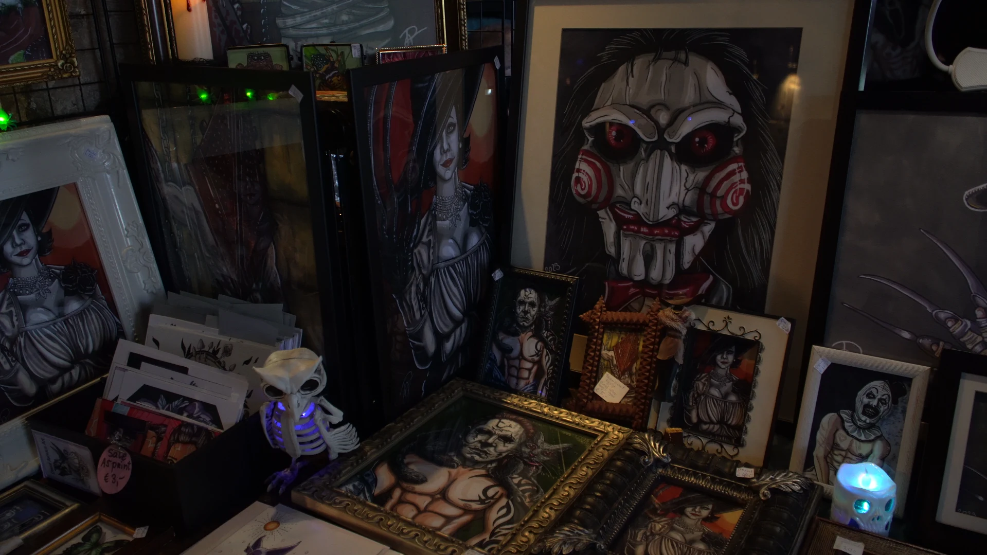 Stand mit gerahmten Horror-Illustrationen, Bildern und kleinen Dekorationsobjekten.
