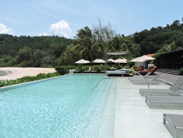 Hotel mit Pool, Liegen, Palmen und Blauer Himmel. Entspannung für die Reisen